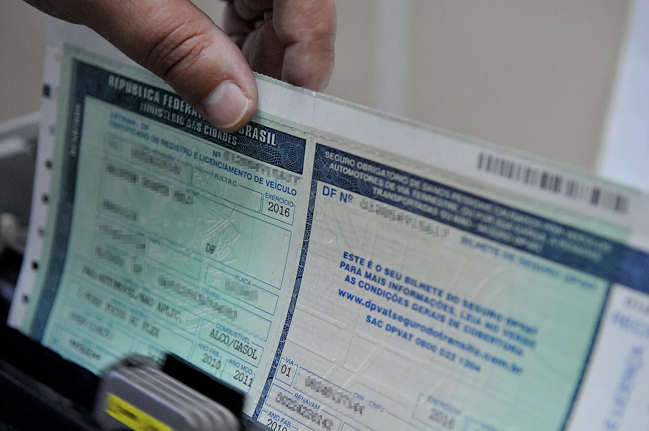 CRLV antigo em papel verde, de 2016, com os dados do veículo borrados